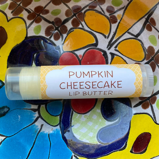 A tube of Pumpkin Cheesecake lip butter on a colorful ceramic plate