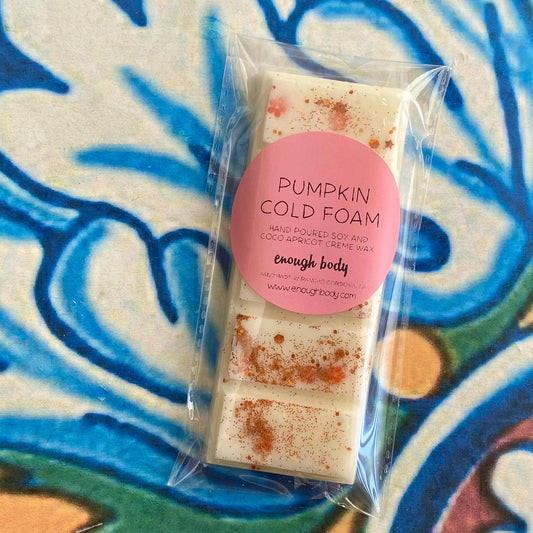 A packaged wax melt snap bar with 'Pumpkin Cold Foam' written on the label, displayed on a colorful patterned background.