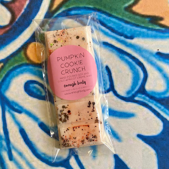 A packaged pumpkin cookie crunch wax melt snap bar with visible glitter on the top surface, placed on a patterned background.