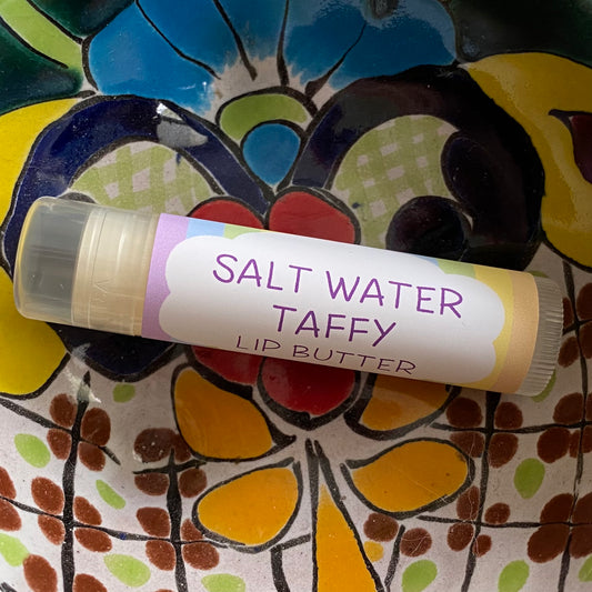 Lip butter labeled 'Salt Water Taffy' on a colorful ceramic plate