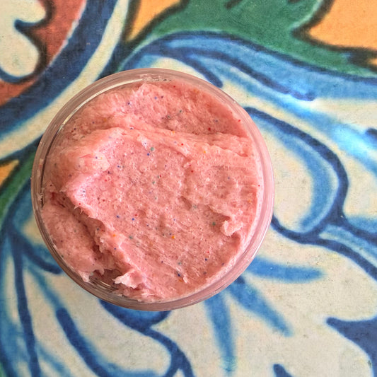 Pink scrub in a jar on a colorful, patterned surface