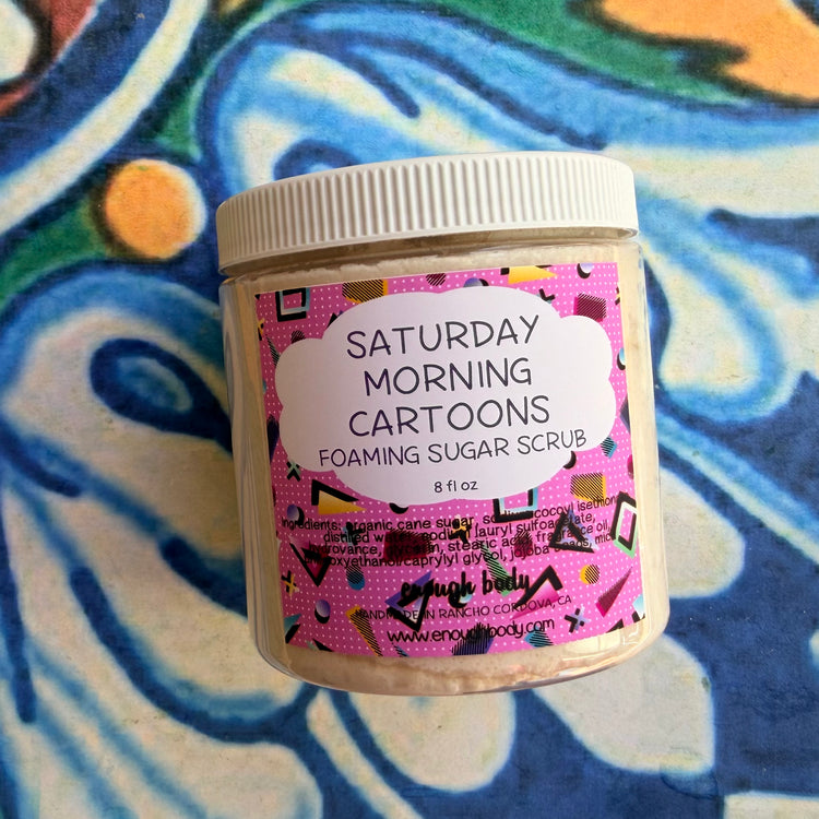 Jar of 'Saturday Morning Cartoons' foaming sugar scrub with a colorful label on a patterned background