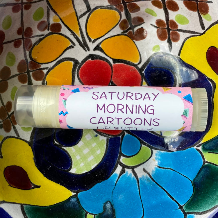 Tube of lip butter labeled saturday morning cartoons placed on a colorful background