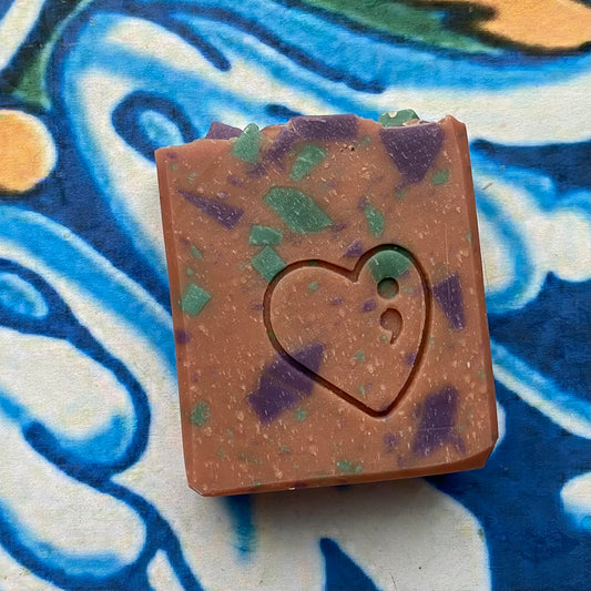 Square soap bar with a heart cutout on a colorful abstract background