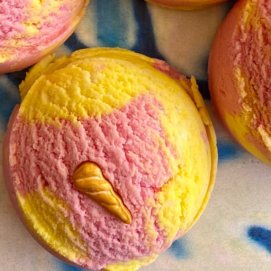 A solid bubble bath scoop with swirls of yellow and pink, resembling a colorful ice cream cone.