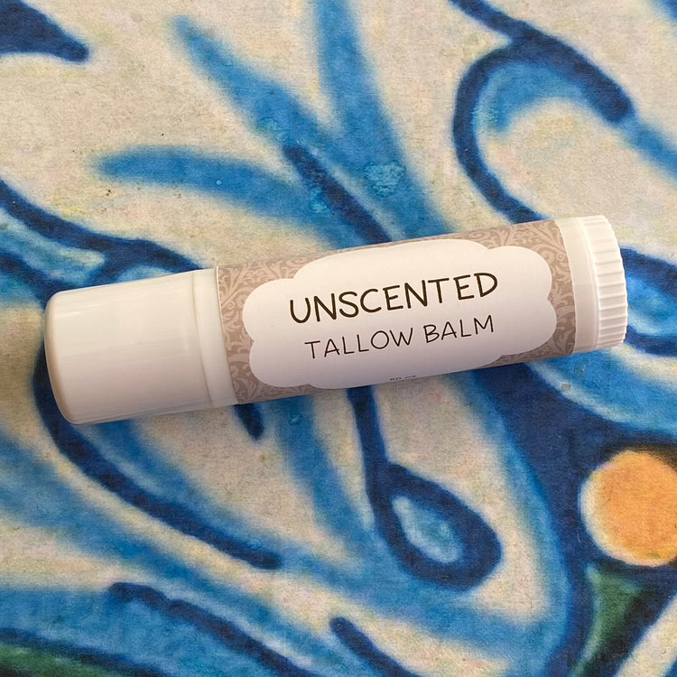 Unscented tallow balm tube on a textured blue and beige background