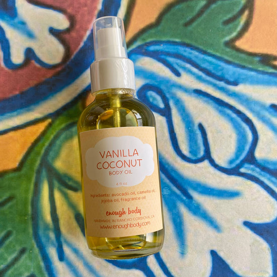 Bottle of Vanilla Coconut body oil with a treatment pump top on a colorful abstract background