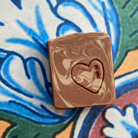 Marbled brown soap bar with a heart cutout on a colorful patterned background