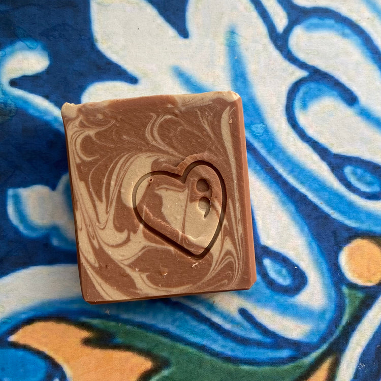 Marbled brown soap with a heart cutout on a colorful abstract background