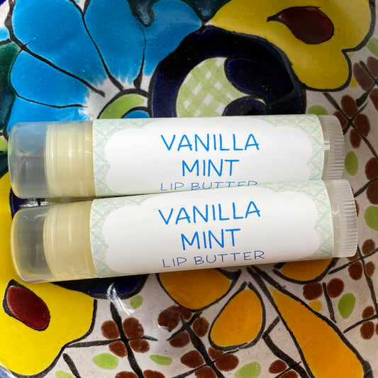 Two tubes of Vanilla Mint Lip Butter placed on a colorful floral background.