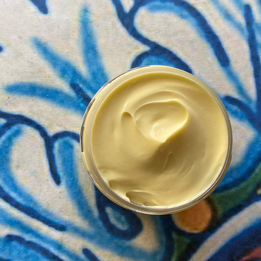 Jar of yellow cream on a textured blue and beige surface