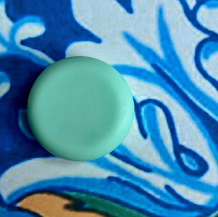 A solid conditioner bar with a minty eucalyptus scent, placed on a background with a blue floral pattern.