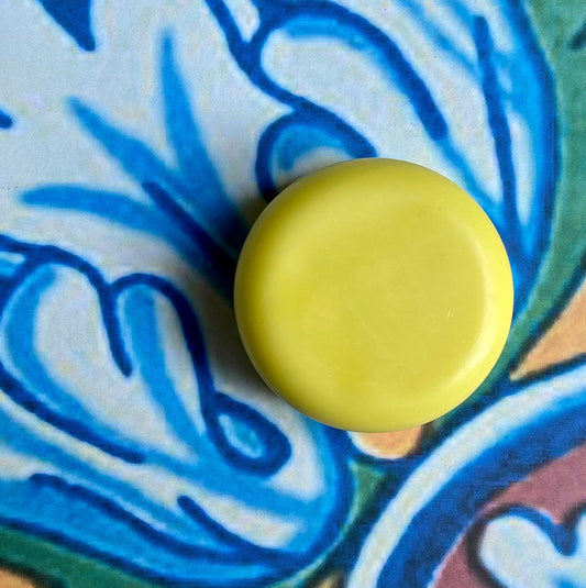A solid conditioner bar with a pineapple mango scent, placed on a background with a blue floral pattern.