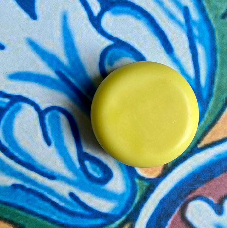 A solid conditioner bar with a pineapple mango scent, placed on a background with a blue floral pattern.