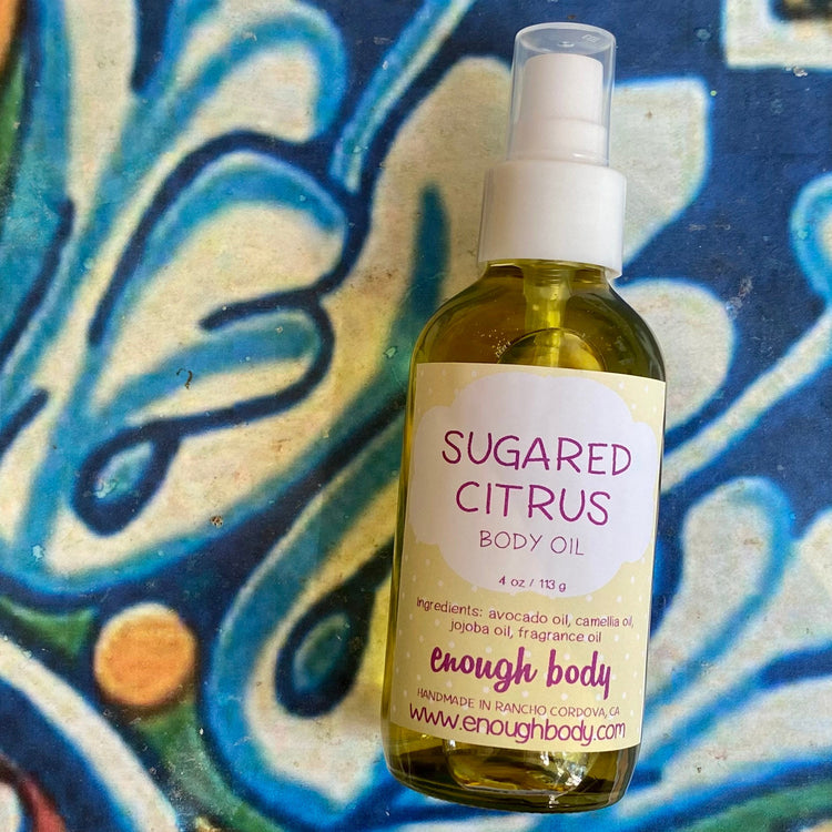 Bottle of Sugared Citrus body oil on a colorful abstract background